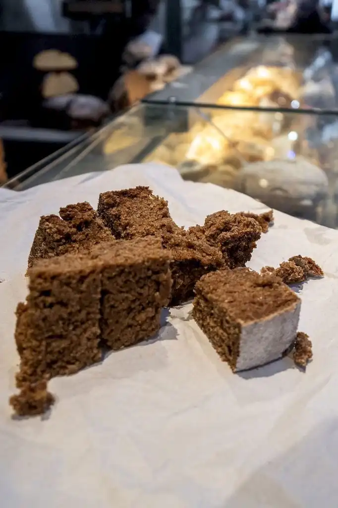 Sliced squares of Portuguese brown sugar cake on parchment paper at a bakery counter