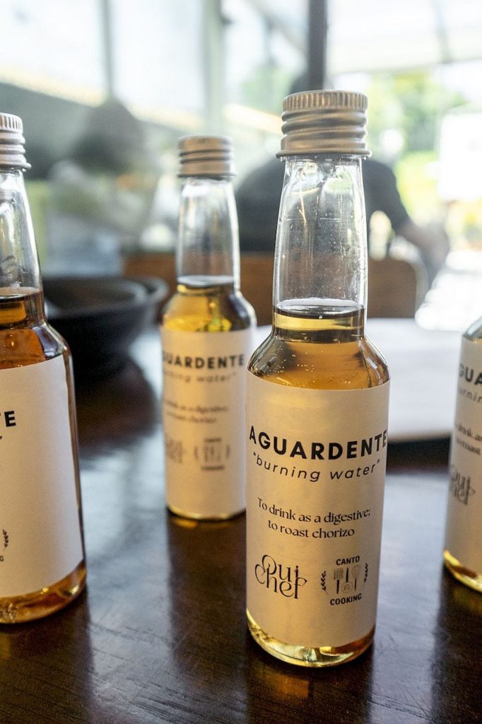 Small bottles of aguardente labeled burning water on a wooden table
