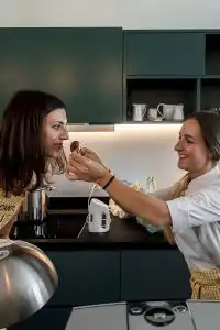 Two guests laughing and sharing a chocolate treat in a cooking class kitchen