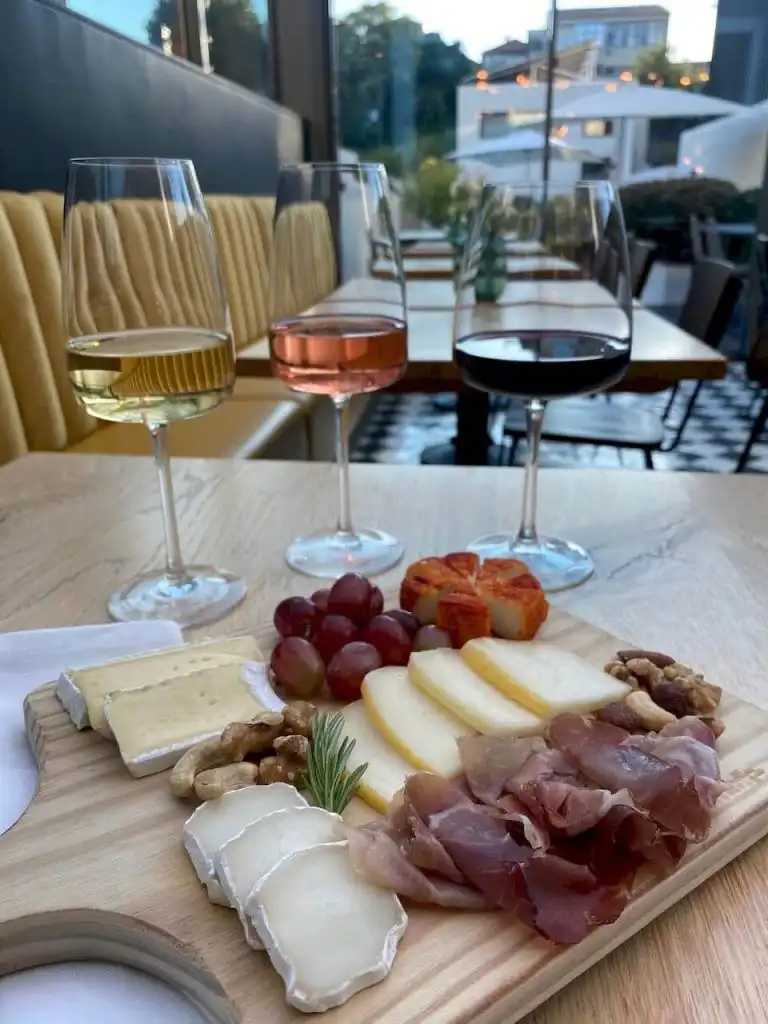 Charcuterie and cheese board with three glasses of white, rosé, and red wine