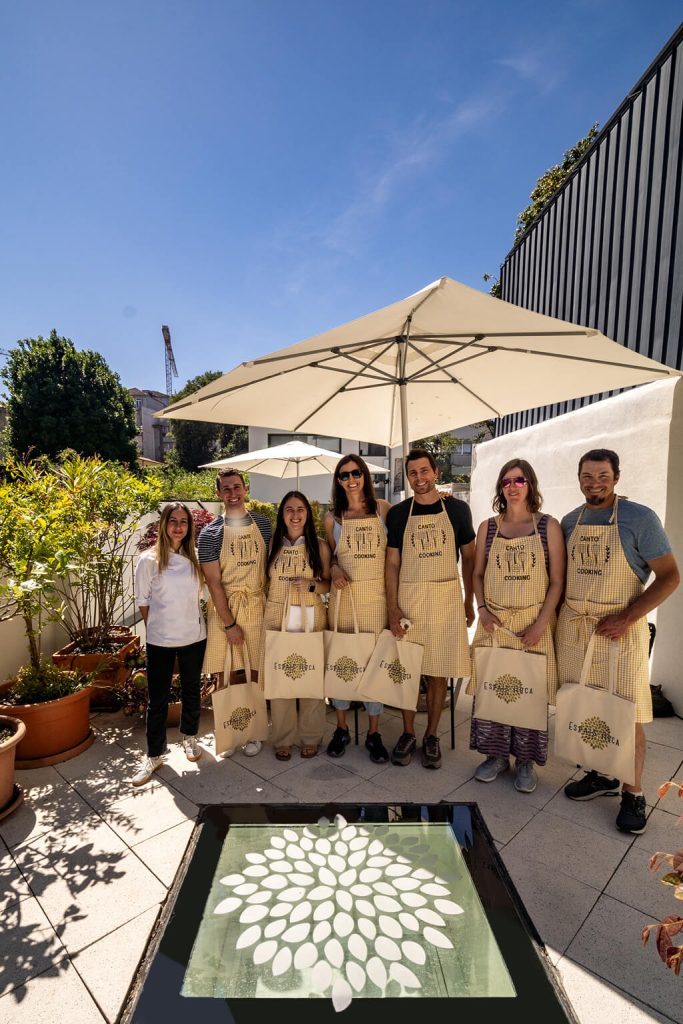 A group of cooking class participants wearing matching aprons on a sunny rooftop terrace