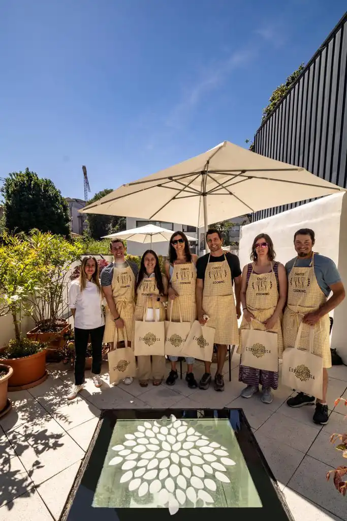 A group of cooking class participants wearing matching aprons on a sunny rooftop terrace