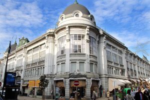 Grand Beaux-Arts corner building with domed tower on a busy Porto street