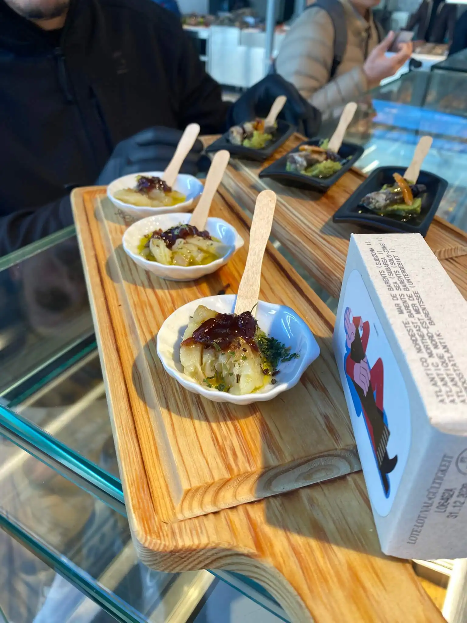 Salt cod tastings served on a wooden board beside a box of Atlantic salted cod in Porto