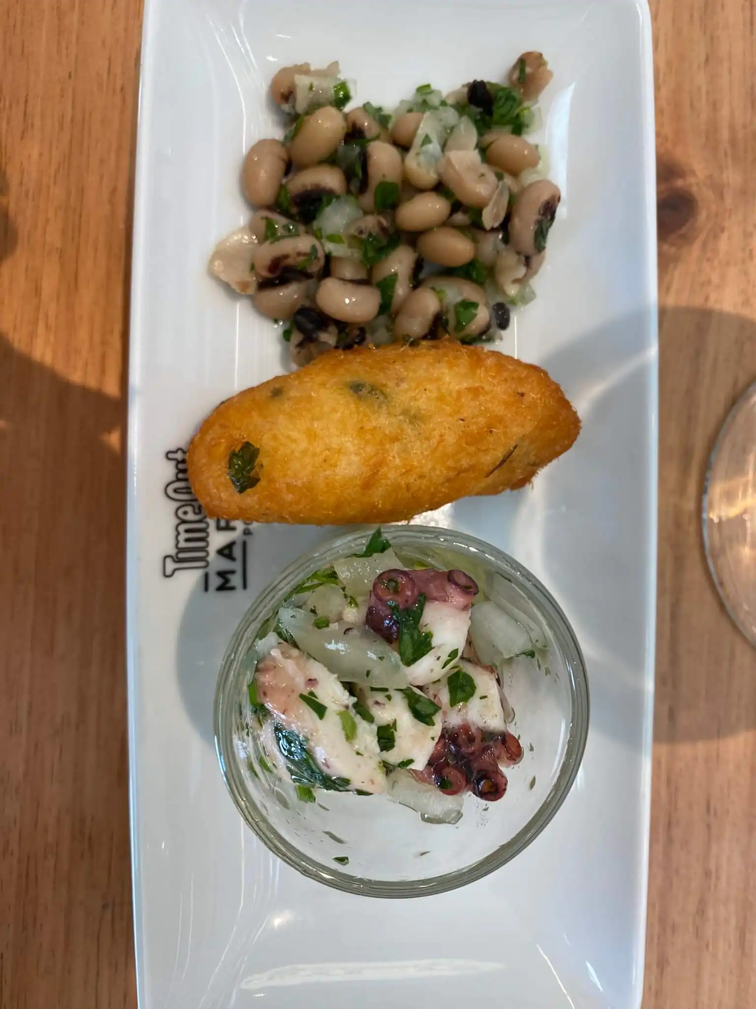 Pastel de bacalhau served with black-eyed bean salad and octopus salad in Porto