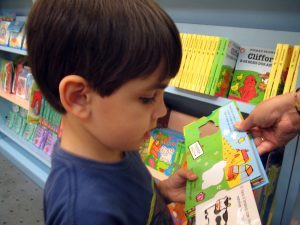 A young child looking at a colourful children's book in a bookshop