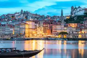 Porto Ribeira waterfront at dusk with colourful buildings reflected in the Douro River