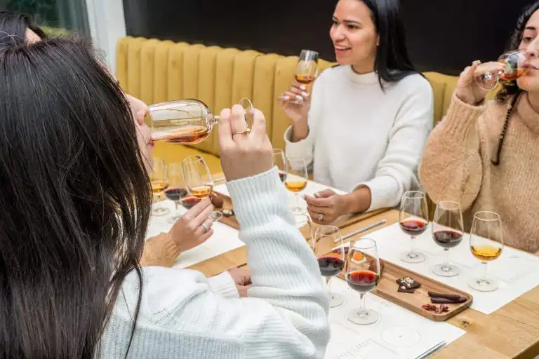 A group of guests tasting amber and red wines paired with chocolate at a tasting table