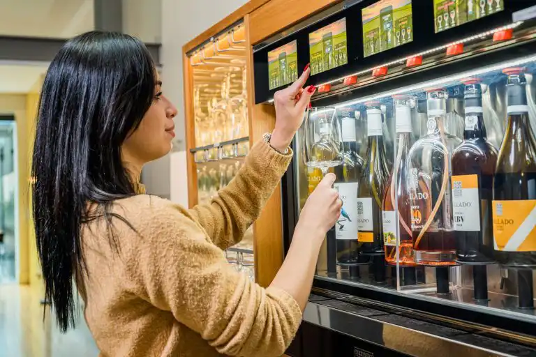 A guest retrieving a wine glass from an automated wine dispenser