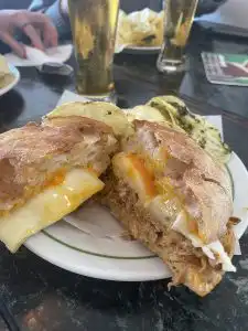 Buffalo chicken sandwich cut in half, showing melted cheese and sauce on ciabatta