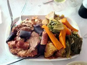 Cozido à portuguesa served on a white platter with carrots, greens, and mixed meats