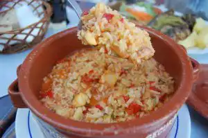 Tomato rice with fish and vegetables served in a terracotta pot