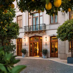 Elegant hotel entrance with warm-lit wooden doors framed by lemon trees on a cobblestone courtyard