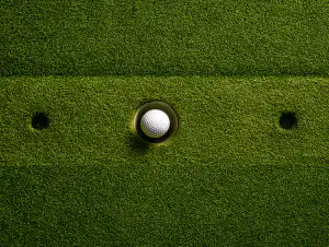 Golf ball resting in the cup on a putting green