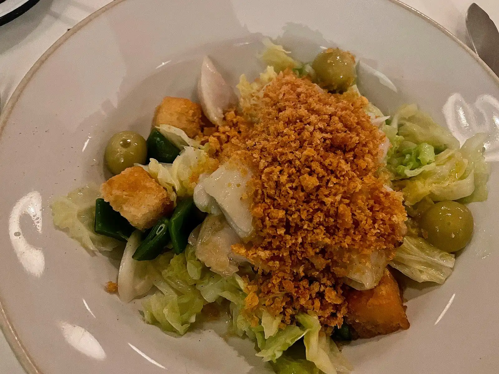 Plated Portuguese salt cod with potatoes, greens, olives and a golden crumb topping