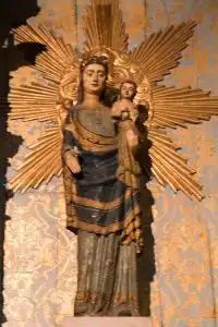 Polychrome wooden statue of the Virgin Mary holding the Christ Child, surrounded by a gilded sunburst halo